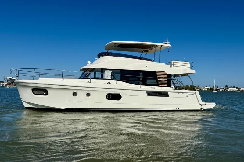 Slide: The Image of 2023 Beneteau Swift Trawler 48 cruising on calm waters under a clear blue sky. - 5