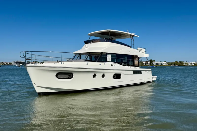Slide: The Image of 2023 Beneteau Swift Trawler 48 cruising on calm waters under a clear blue sky. - 6