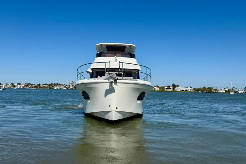 Slide: The Image of 2023 Beneteau Swift Trawler 48 on calm water under clear blue sky. - 7