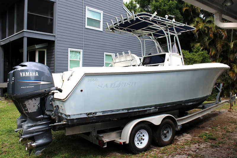 Slide: The Image of 2008 Sailfish 2660 CC boat on trailer with Yamaha outboard motor, parked near a house. - 3