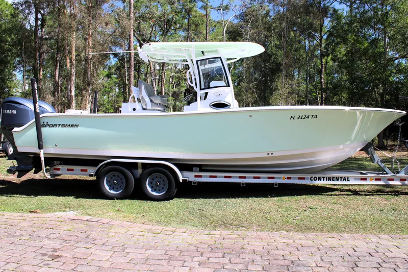 Slide: The Image of 2021 Sportsman Open 282 Center Console boat on trailer in wooded area. - 2