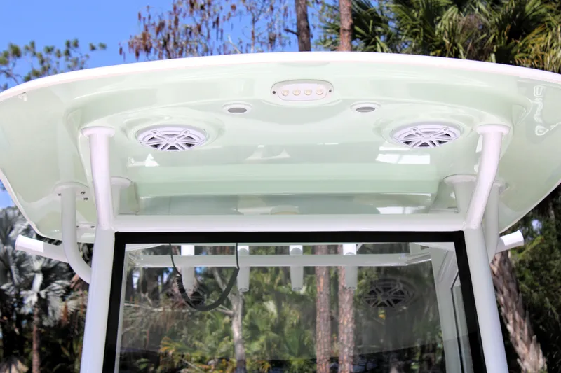 Slide: The Image of 2021 Sportsman Open 282 Center Console T-top with speakers and lights, surrounded by trees. - 21