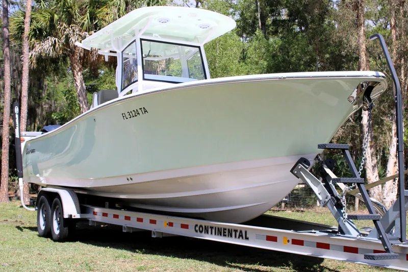 Slide: The Image of 2021 Sportsman Open 282 Center Console boat on trailer in wooded area. - 3