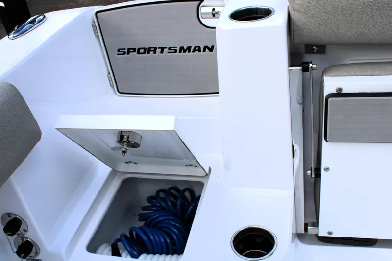 Slide: The Image of 2021 Sportsman Open 282 Center Console boat interior with storage compartment and coiled hose. - 30