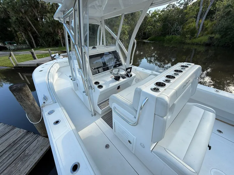 Slide: The Image of 2023 SeaHunter 28 Floridian boat interior with helm, seating, and rod holders by a dock. - 37