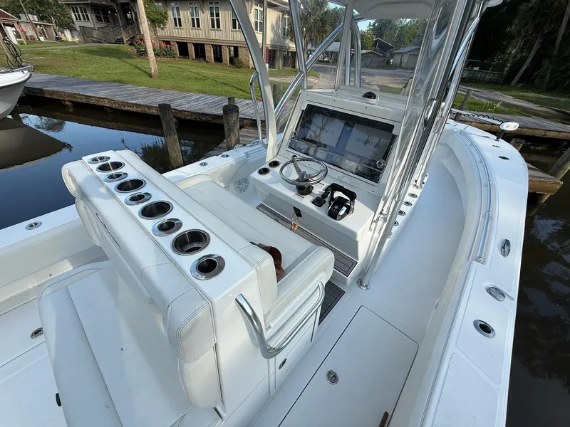 Slide: The Image of 2023 SeaHunter 28 Floridian boat interior with helm, seating, and cup holders by a dock. - 38