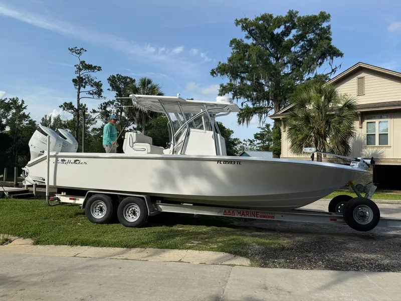 Slide: The Image of 2023 SeaHunter 28 Floridian boat on trailer, parked outdoors near trees and a house. - 9