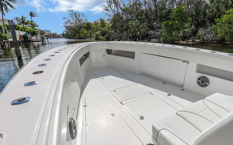 Slide: The Image of 2019 SeaVee 390Z boat deck with seating, surrounded by lush greenery and calm waters. - 11