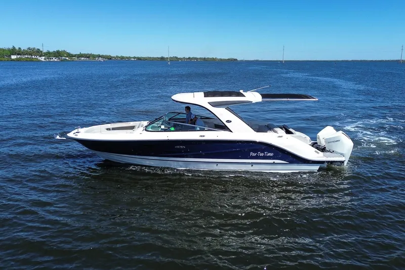 Slide: The Image of 2023 Sea Ray SLX 310 Outboard cruising on open water under clear blue skies. - 2