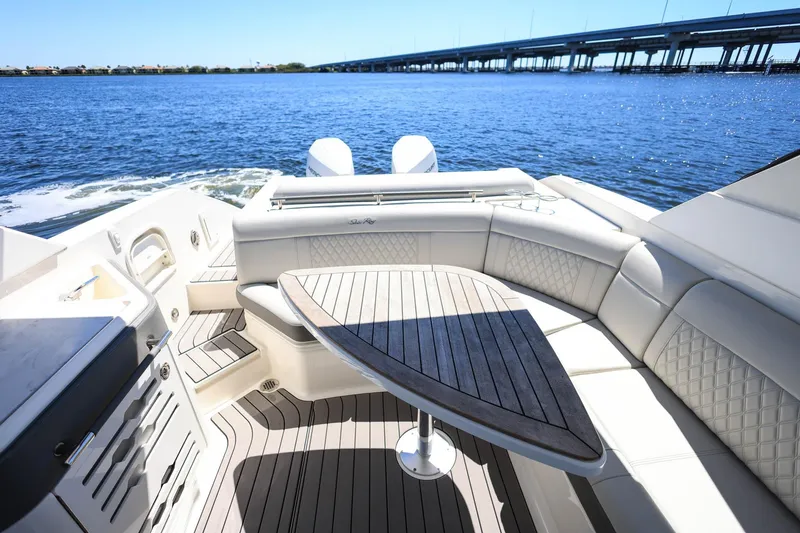 Slide: The Image of 2023 Sea Ray SLX 310 Outboard boat interior with elegant seating and wooden table. - 22