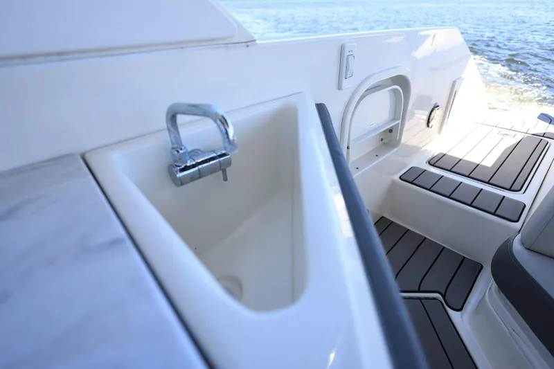 Slide: The Image of 2023 Sea Ray SLX 310 Outboard boat interior with sink and seating area. - 29