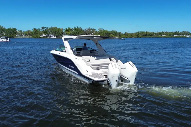 Slide: The Image of 2023 Sea Ray SLX 310 Outboard cruising on a serene lake under a clear blue sky. - 3