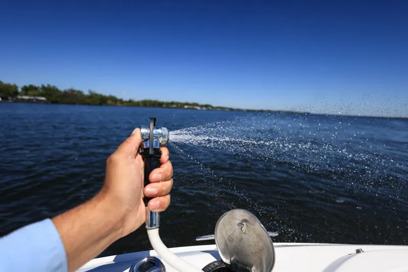 Slide: The Image of Hand spraying water from a 2023 Sea Ray SLX 310 Outboard boat on a sunny day. - 9