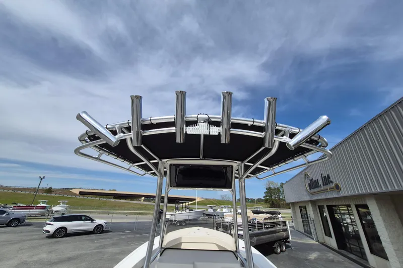 Slide: The Image of 2026 May-Craft 245 Offshore CC boat with T-top and rod holders, parked outdoors. - 18