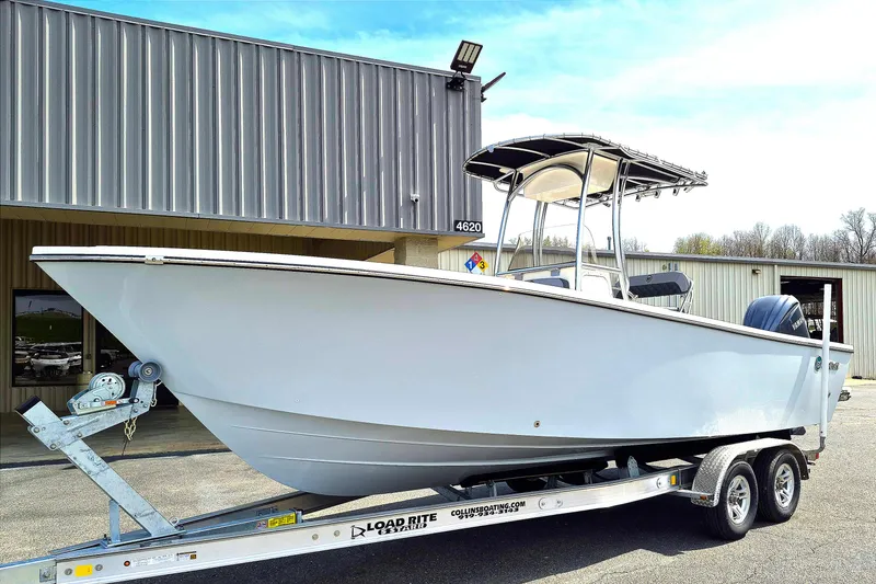 Slide: The Image of 2026 May-Craft 245 Offshore CC boat on trailer outside a metal building. - 2