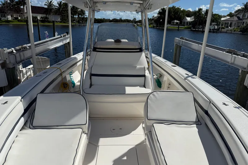 Slide: The Image of 2009 Intrepid 323 Open boat interior with white seating, docked by a serene waterfront. - 16