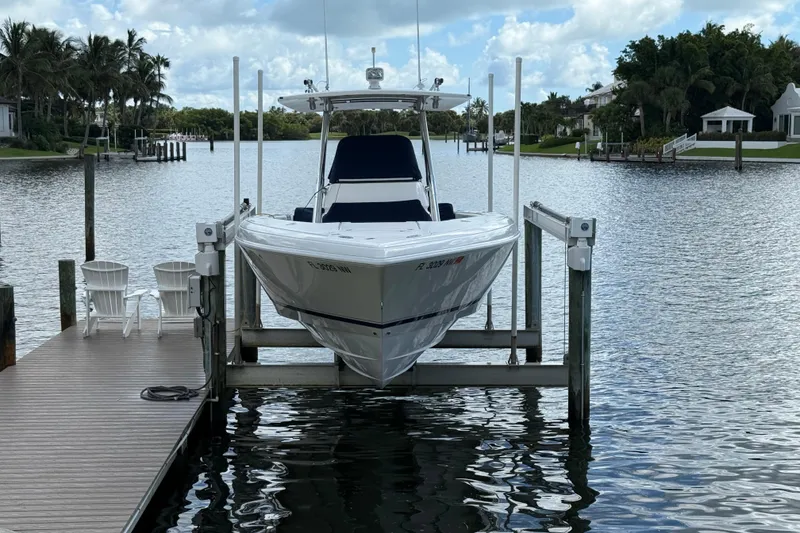 Slide: The Image of 2009 Intrepid 323 Open boat docked on a lift by a scenic waterfront. - 18