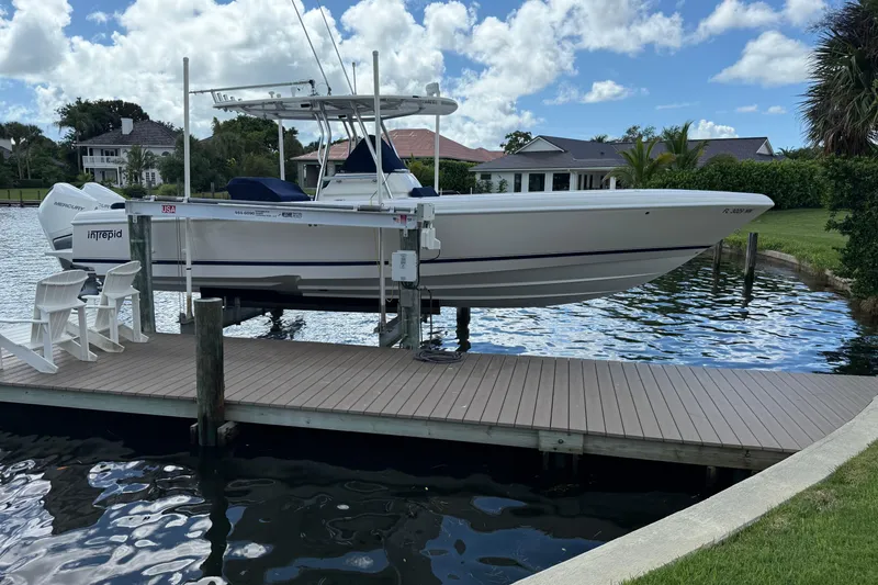 Slide: The Image of 2009 Intrepid 323 Open boat docked on a lift by a waterfront property. - 20