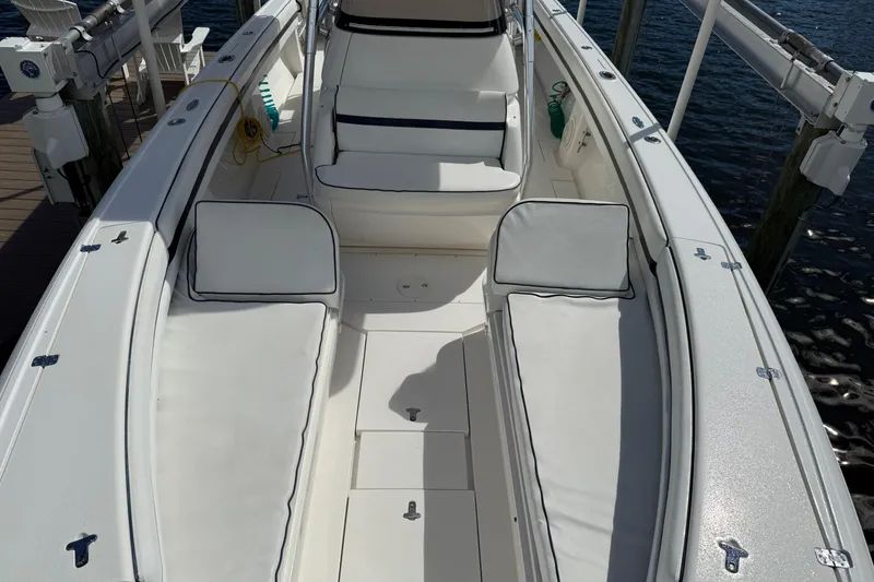 Slide: The Image of 2009 Intrepid 323 Open boat interior with white seating and deck, docked by water. - 7