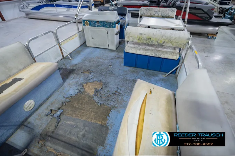 Slide: The Image of 1993 Godfrey SW 180 pontoon boat interior with worn seats and flooring in a showroom. - 12