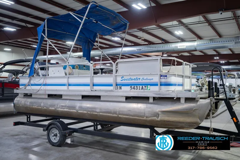 Slide: The Image of 1993 Godfrey SW 180 pontoon boat with blue canopy on trailer in indoor showroom. - 6