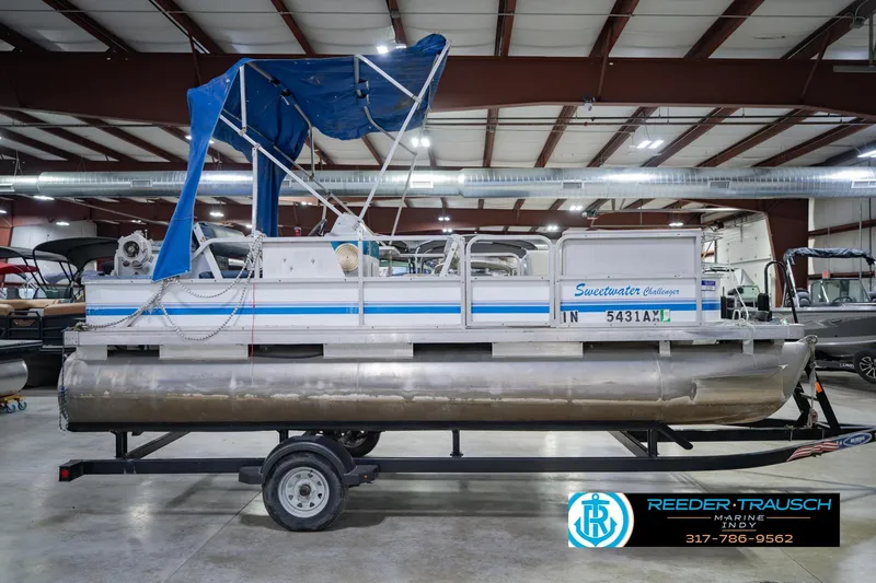 Slide: The Image of 1993 Godfrey SW 180 pontoon boat with blue canopy in indoor showroom. - 7