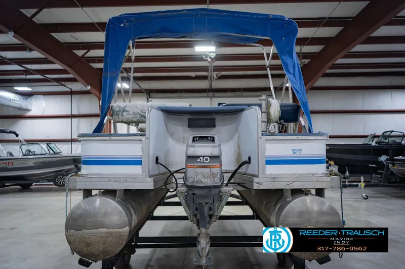 Slide: The Image of 1993 Godfrey SW 180 pontoon boat with blue canopy in indoor storage facility. - 9