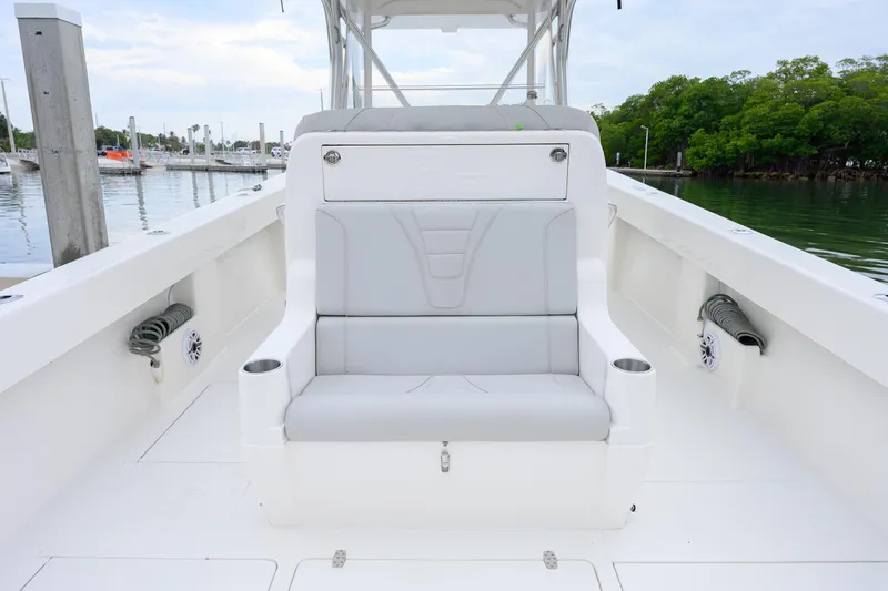 Slide: The Image of 2025 SeaVee 370Z boat interior with cushioned seating and cup holders, docked by the water. - 7