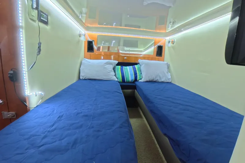 Slide: The Image of Interior cabin of 2012 Regal 46 Sport Coupe with twin beds and blue bedding. - 10