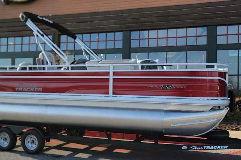 The Image of 2026 Sun Tracker Party Barge 22 XP3 pontoon boat on trailer, red and silver design. - 0