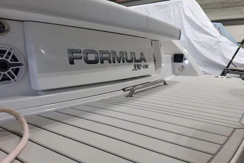 Slide: The Image of 2026 Formula 330 Crossover Bowrider OB boat, rear view with branding and deck details. - 12