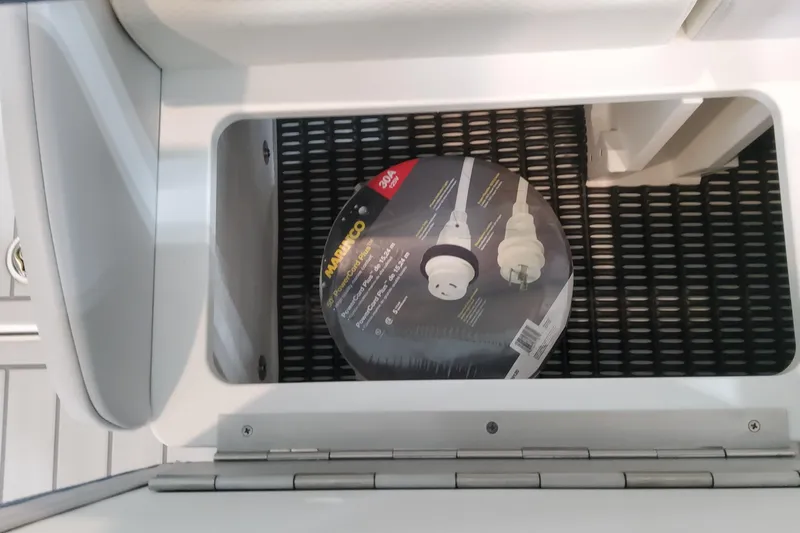 Slide: The Image of Storage compartment in a 2026 Formula 330 Crossover Bowrider OB with power cord. - 76