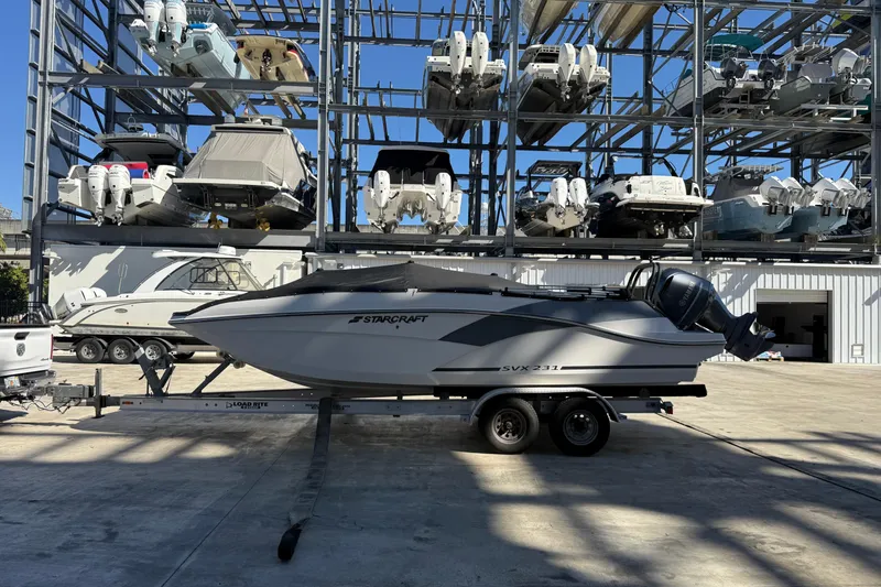 The Image of 2023 Starcraft SVX 231 OB boat on trailer in marina storage facility. - 1