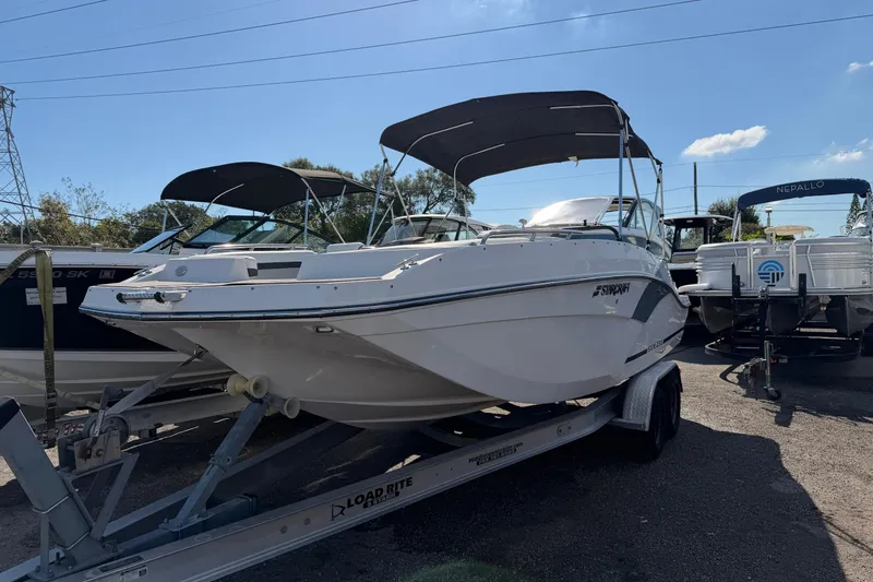 Slide: The Image of 2023 Starcraft SVX 231 OB boat on trailer, parked outdoors under clear sky. - 4