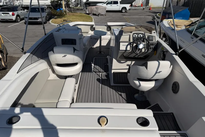 Slide: The Image of 2023 Starcraft SVX 231 OB boat interior with seating and steering wheel in a marina. - 8