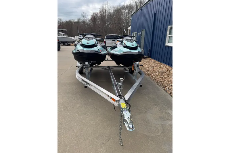 Slide: The Image of 2024 Sea Doo Wake 170 jet skis on a trailer, parked outside a blue building. - 12