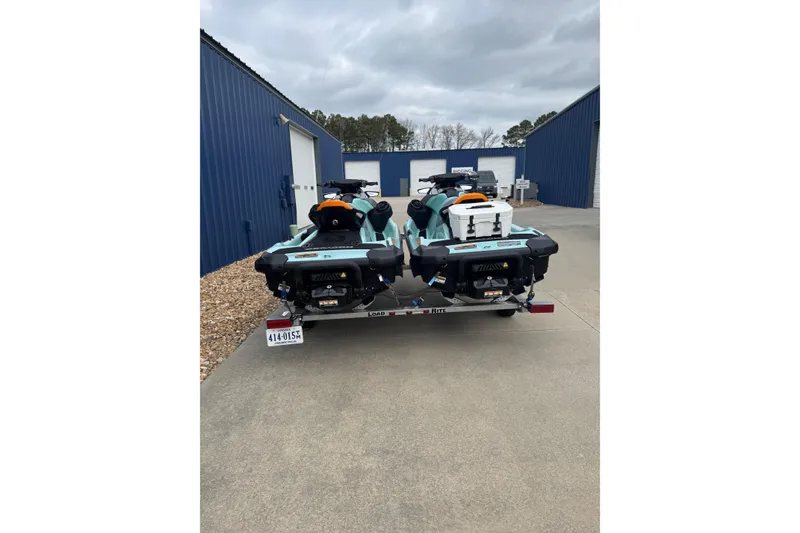 Slide: The Image of 2024 Sea Doo Wake 170 jet skis on trailer outside blue storage units. - 13