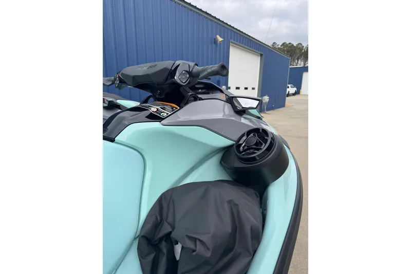 Slide: The Image of 2024 Sea Doo Wake 170 jet ski, close-up of handlebars and speaker, parked outside. - 5