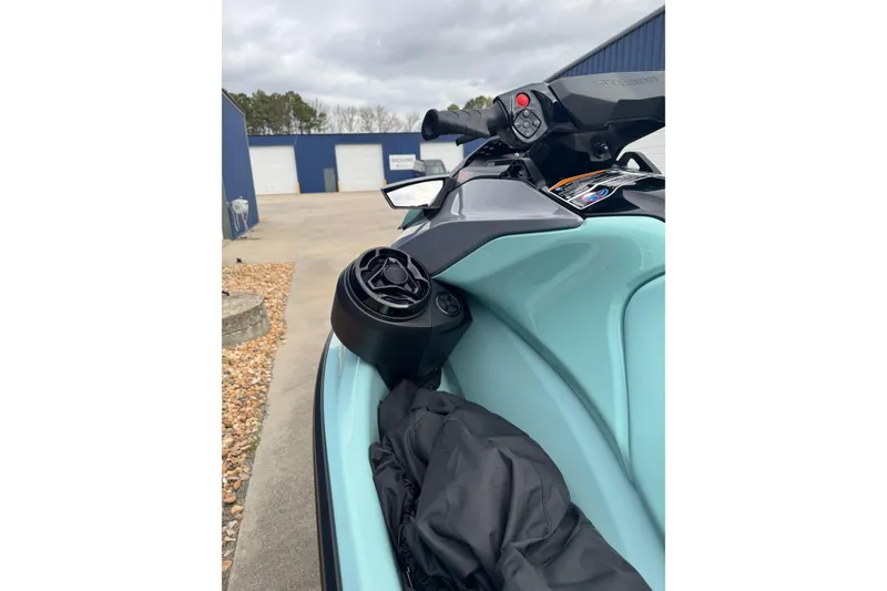 Slide: The Image of 2024 Sea Doo Wake 170 jet ski, close-up of handlebars and speaker, parked outdoors. - 8