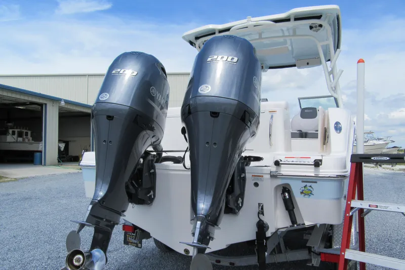 Slide: The Image of 2018 Robalo R247 Dual Console with twin Yamaha 200 engines at a marina. - 2