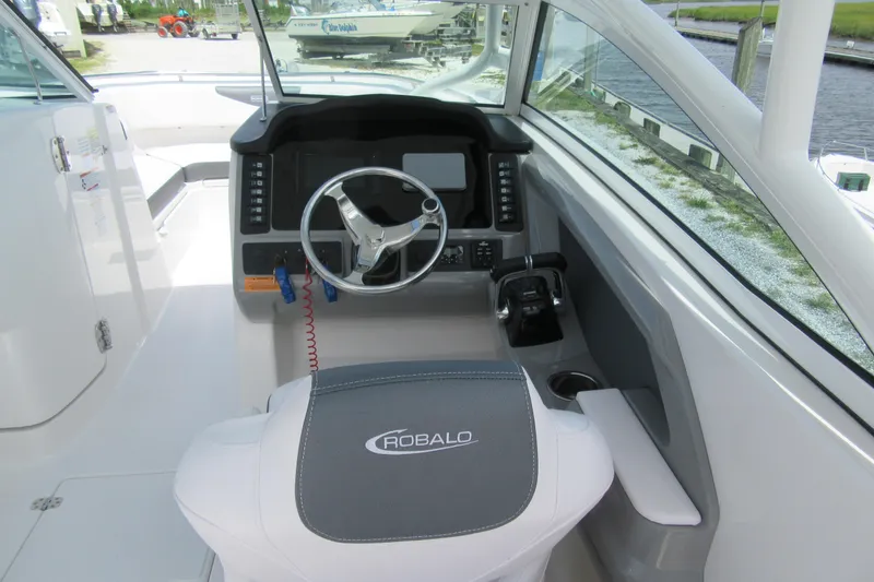 Slide: The Image of 2018 Robalo R247 Dual Console boat cockpit with steering wheel and controls. - 3
