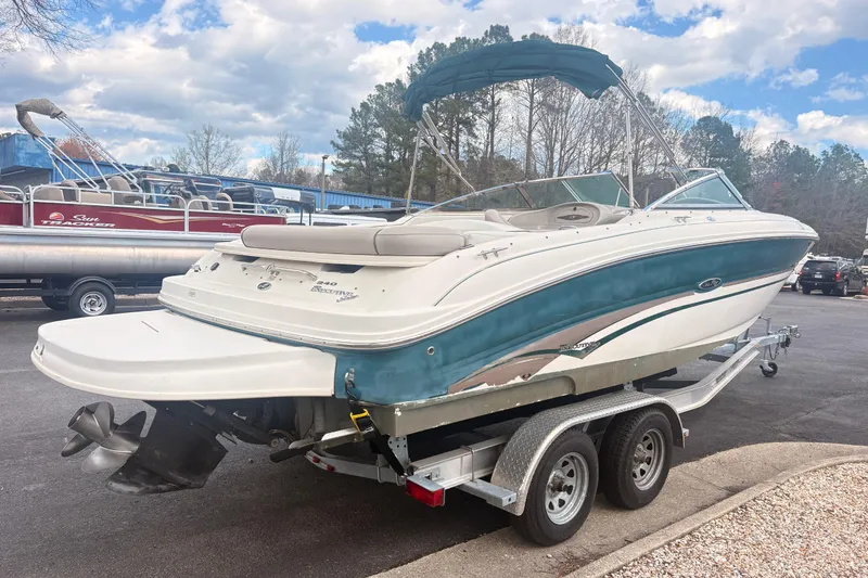 Slide: The Image of 2003 Sea Ray 240 Bow Rider boat on trailer, parked outdoors under cloudy sky. - 2