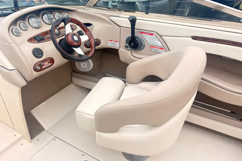 Slide: The Image of 2003 Sea Ray 240 Bow Rider helm with beige seating and wood-accented dashboard. - 5
