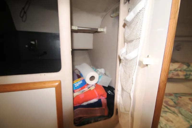 Slide: The Image of Storage compartment in 1996 Sea Ray Sundancer 330 with towels and household items. - 10