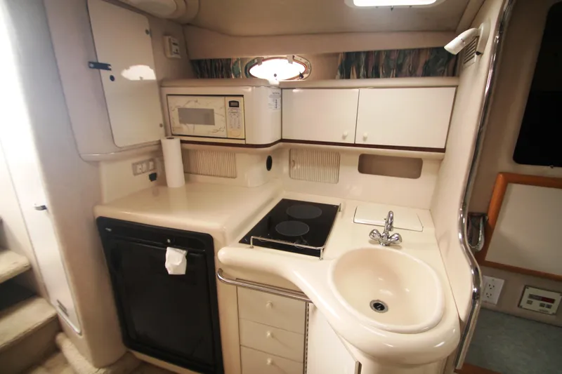 Slide: The Image of 1996 Sea Ray Sundancer 330 yacht kitchen with stove, sink, microwave, and storage cabinets. - 15