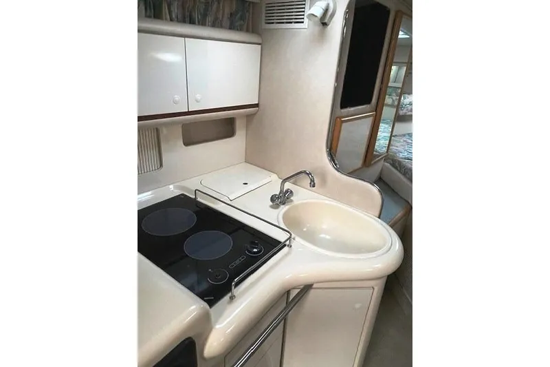 Slide: The Image of 1996 Sea Ray Sundancer 330 yacht kitchen with stove, sink, and storage cabinets. - 17
