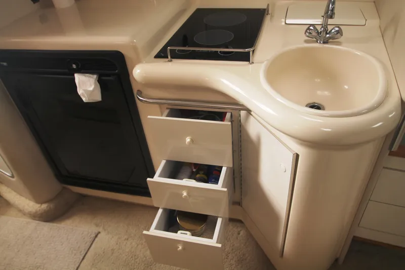 Slide: The Image of 1996 Sea Ray Sundancer 330 galley with sink, stove, and open storage drawers. - 19