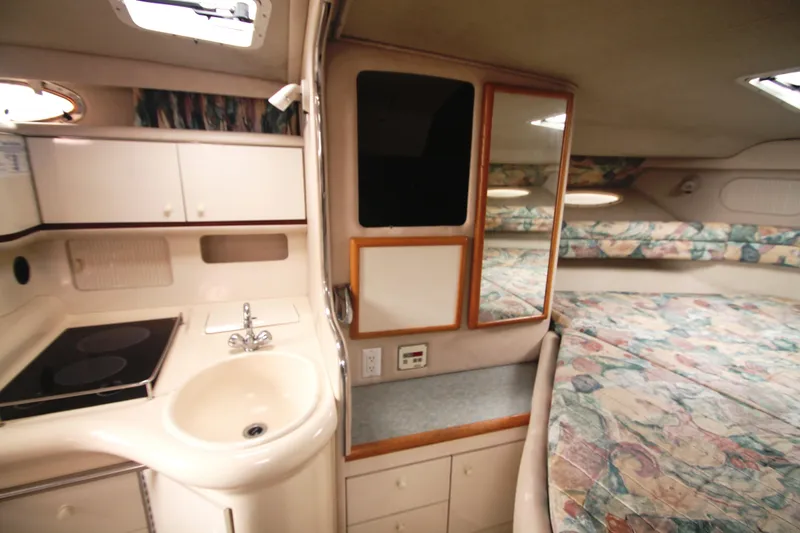 Slide: The Image of Interior of a 1996 Sea Ray Sundancer 330, featuring a compact kitchen and cozy sleeping area. - 4