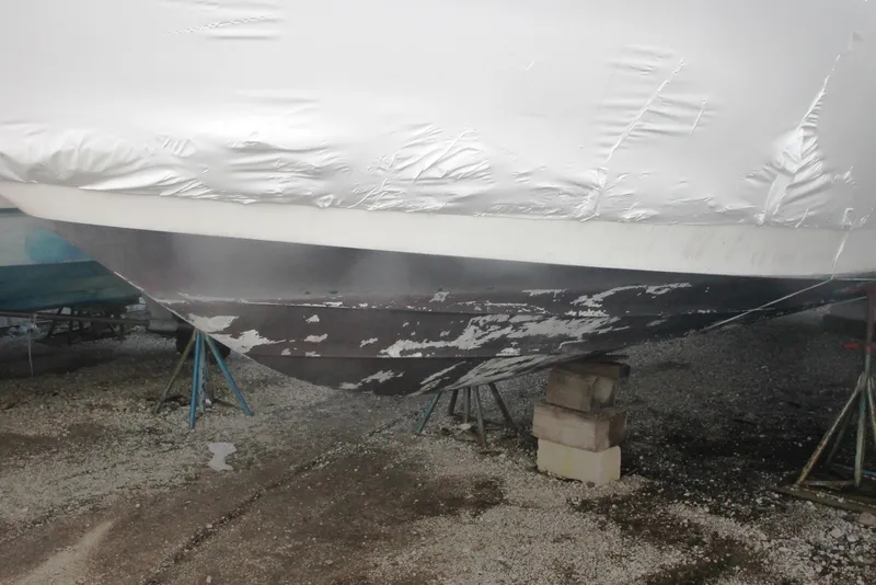 Slide: The Image of 1996 Sea Ray Sundancer 330 boat hull on stands, showing wear and peeling paint. - 54