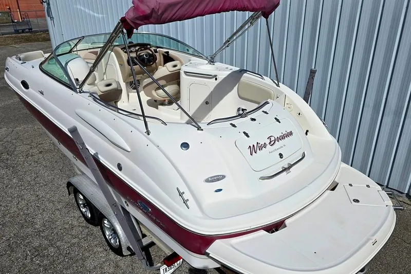 Slide: The Image of 2005 Chaparral Sunesta 254 boat with maroon accents and canopy, parked on a trailer. - 1
